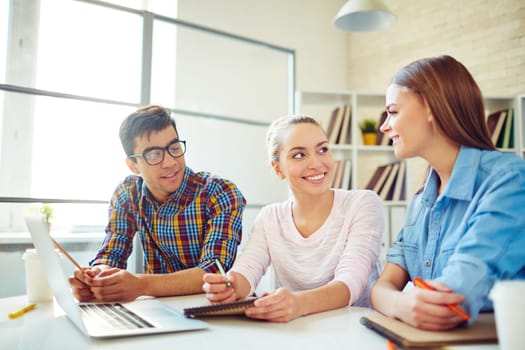 Group of happy teenagers discussing home assignment or notes