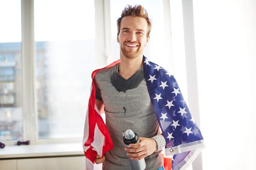 Young man wrapped in USA flag looking at camera