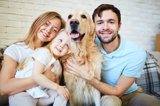 Modern family with dog looking at camera during home rest