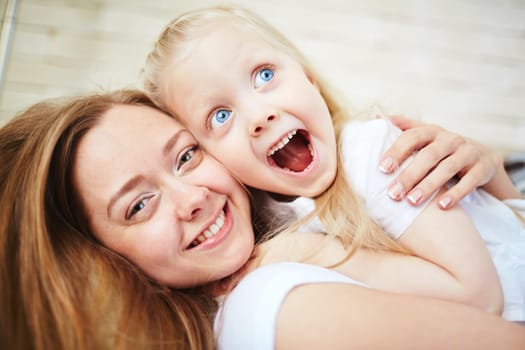 Affectionate female embracing her amazed little daughter