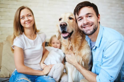 Young man embracing dog with happy woman and girl on background
