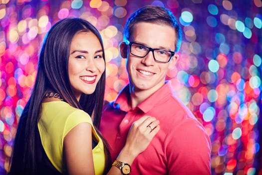 Amorous young couple looking at camera while enjoying party