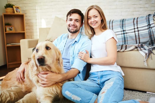 Happy young couple and their pet enjoying home rest on weekend