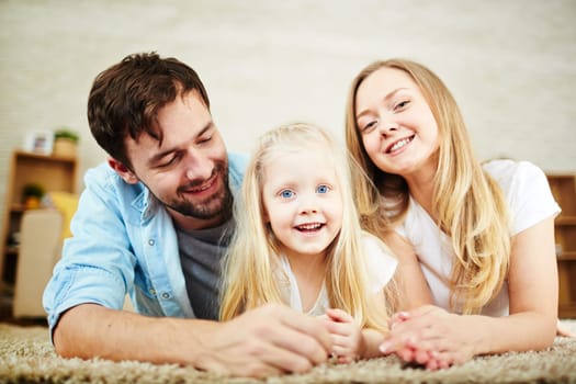 Cheerful couple and cute girl relaxing at home