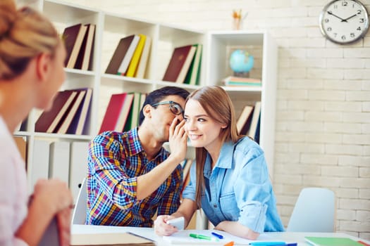 Handsome guy whispering secret to cute girl