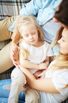Cute little girl sleeping on her parents knees