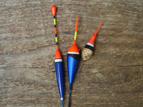 three fishing bobbers on wooden background close to still life