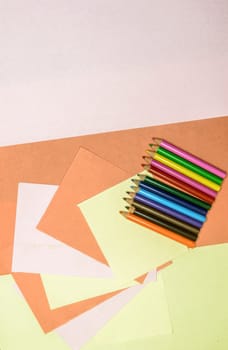 Color pencils lying on colorful DIY Craft Paper. Art and craft hobbies, design, background concepts. Table top view. Flat lay.