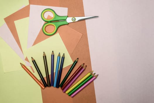 Colour paper, scissors, school stationery supplies, pencils, paint, and ruler lying on table. Origami DIY tutorial for kids background. Back to school concept. Directly above. Flat lay.