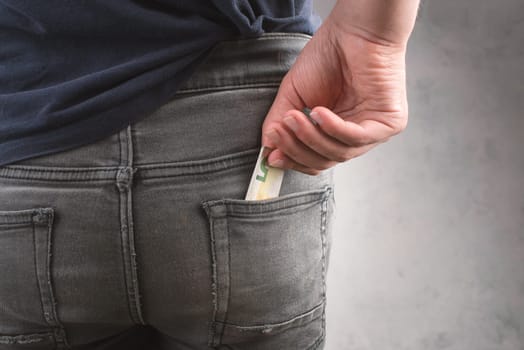 Putting an Euro bill into a jeans pocket, teenager, male