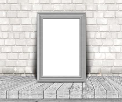 3D render of a blank silver picture frame on a wooden table leaning against a brick wall