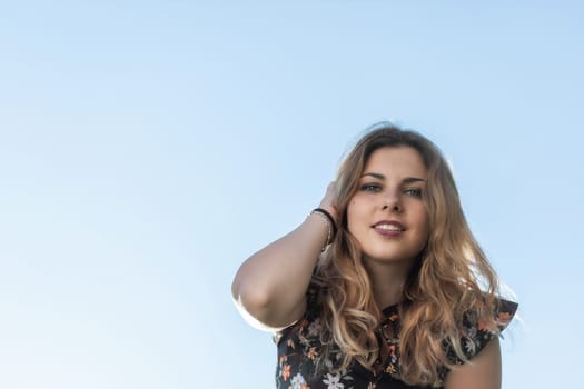 Portrait of smiling attractive young woman. Blue sky in the background. Horizontally.