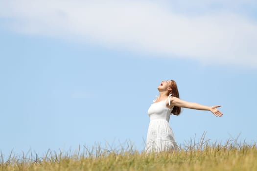 Excited woman screaming to the air outstretching arms in a wheat field