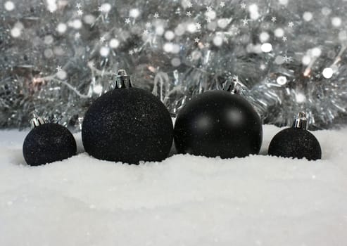 Black Christmas baubles nestled in snow