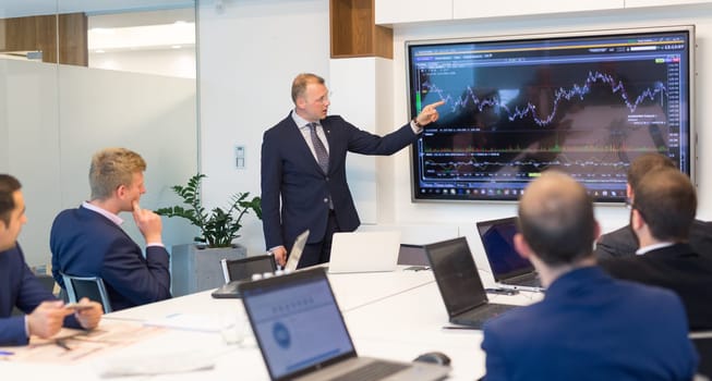 Business man making a presentation at office. Business executive delivering a presentation to his colleagues during meeting or in-house business training, explaining business plans to his employees.