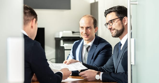 Team of confident successful business people reviewing and signing a contract to seal the deal at business meeting in modern corporate office. Business and entrepreneurship concept.