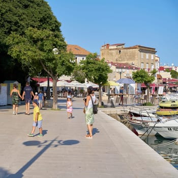 Tourists on the popular promenade in the port of the town of Krk in Croatia