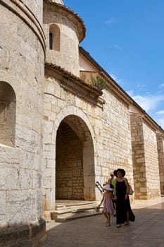 Tourists at the Cathedral of St. Quirinus in the old town of Krk in Croatia on a hot summer day