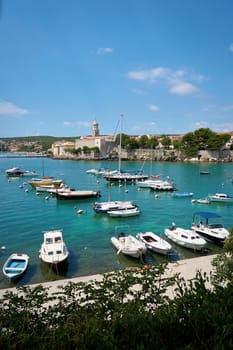 Boats in a bay in front of the old town of Krk on the coast of the Adriatic Sea in Croatia