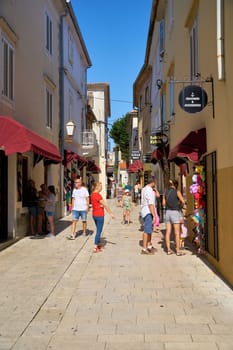 Tourists in an old town alley with stores in Krk in Croatia