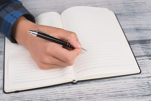 Writing into a book, empty copy space for text, hand with a pen