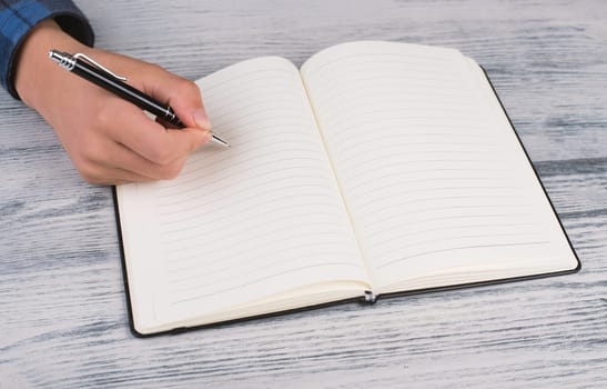 Writing into a book, empty copy space for text, hand with a pen