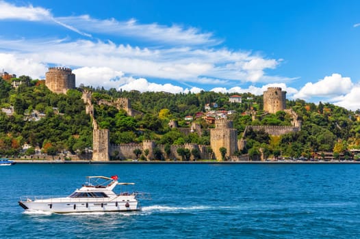 The ship sails in the Bosphorus strait by Rumeli Hisari castle, Istanbul.