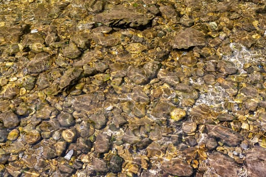 Pebbles under the water surface of a stream as a background