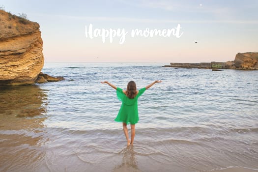 Happy brunette girl in a beautiful green dress runs to the sea. Lettering happy moment