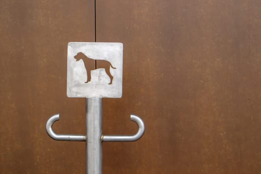 Close-up of an outdoor dog parking sign. A place for a leash for dogs waiting for their owners on the street. Attach a leash, in public places or at the entrance to the store. Copy space