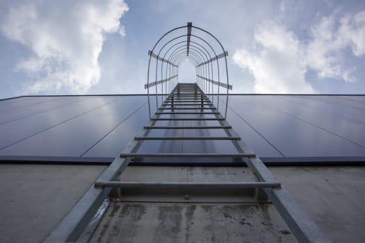 Fire escape on the industrial building above, bottom view. Stainless steel handrails, roof ladder. Detail view of stairs with safety cage. Building construction concept