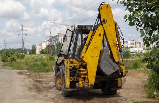 Excavator on a construction site against the background of the sky. Heavy machinery at work. A large yellow construction vehicle at a construction site. Industrial image