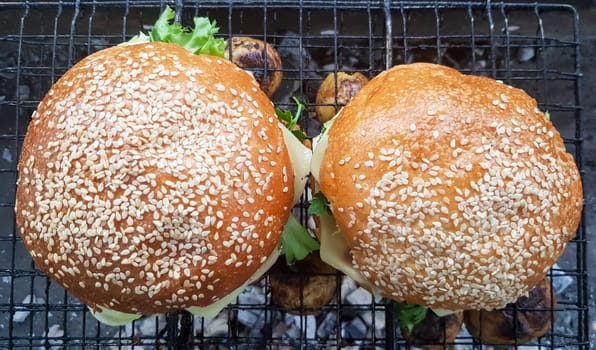 Close-up of two large DIY hamburgers in the park on a barbecue, rest and cooking on a picnic in the summer, food, delicious, bright colors. Unhealthy food concept. Fast food. Flat lay