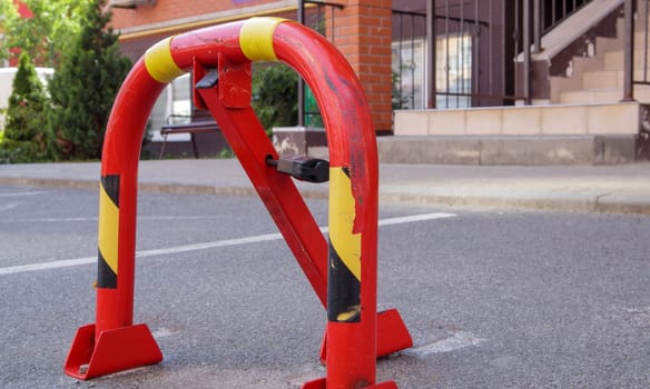 Manual red metal parking barrier with lock. Parking lock device. Parking barrier installed. A foldable barrier prevents the vehicle from stopping at this point. Reserved seat
