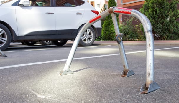 Manual gray galvanized metal parking barrier with lock. Parking lock device. Parking barrier installed. A foldable barrier prevents the vehicle from stopping at this point. Reserved seat