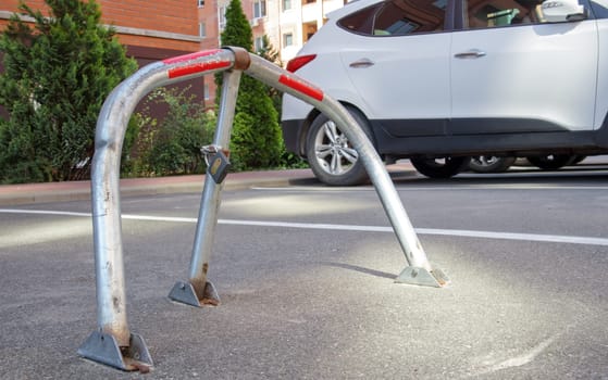 Manual gray galvanized metal parking barrier with lock. Parking lock device. Parking barrier installed. A foldable barrier prevents the vehicle from stopping at this point. Reserved seat