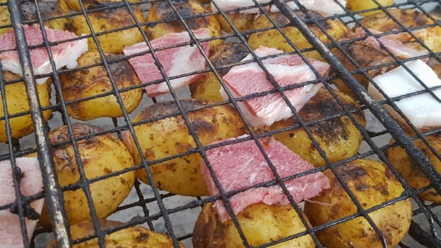 Grilled potatoes with bacon, whole baked on the barbecue grill. Selective focus. Whole small potatoes with bacon bits and grilled. Baked potatoes with grilled bacon