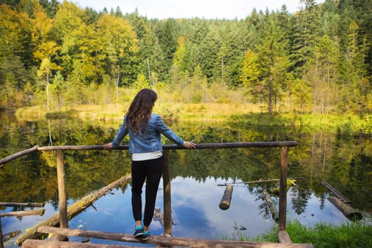girl stands on the bridge and looks at the lake-Carpathians, Ukraine.