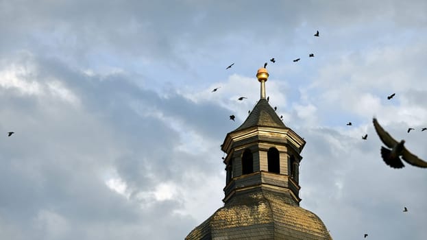 Birds gather on the top of a church tower during storms