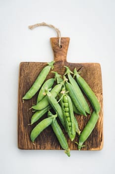 Fresh harvested peas on a wooden vintage cutting board on a table