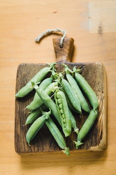 Fresh harvested peas on a wooden vintage cutting board on a table
