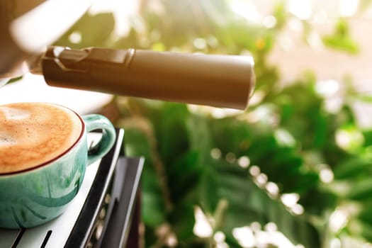 Green cup of coffee on coffee maker machine with dispenser. Mug full of espresso, americano or cappuccino coffee. Blurred background. Morning coffee in the stylish kitchen, cafe or restourant.