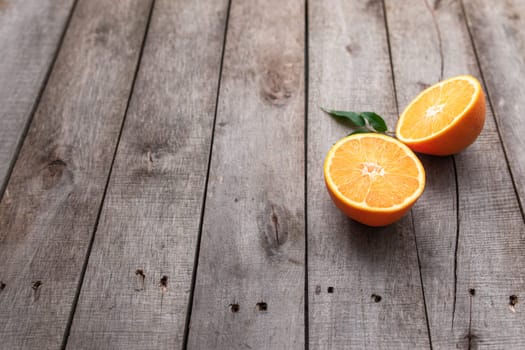 Fresh orange fruit halves or cuts with green leaf on old wooden background table. High quality photo