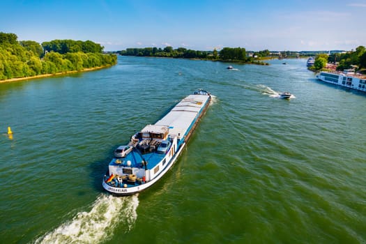 Speyer, Germany - August 21, 2021: Transport of goods on river Rhine, ferry and cruise vessel and boats