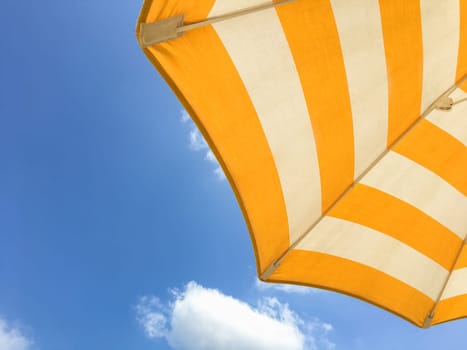 Yellow beach umbrella on a sunny day. Bright colored umbrella on the beach.