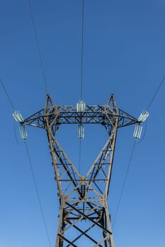 Electricity pylon silhouetted against blue sky background. Copy space.