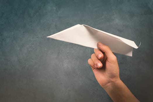 Holding a aper airplane in the handon a textured background, empty copy space for text