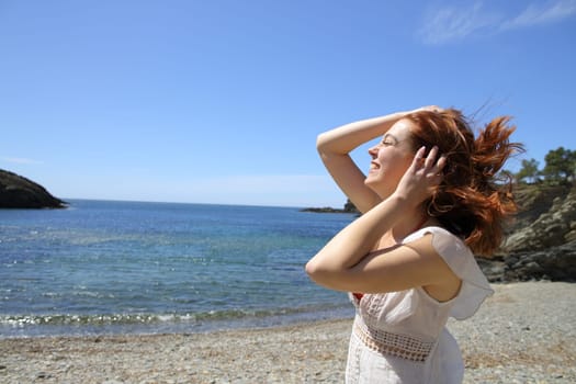Happy woman touching tousled hair in a windy beach day on summer vacation