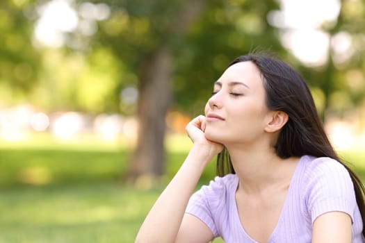Satisfied asian woman resting relaxing with closed eyes in a park