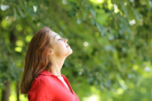 Profile of a woman in red breathing fresh air in a green park